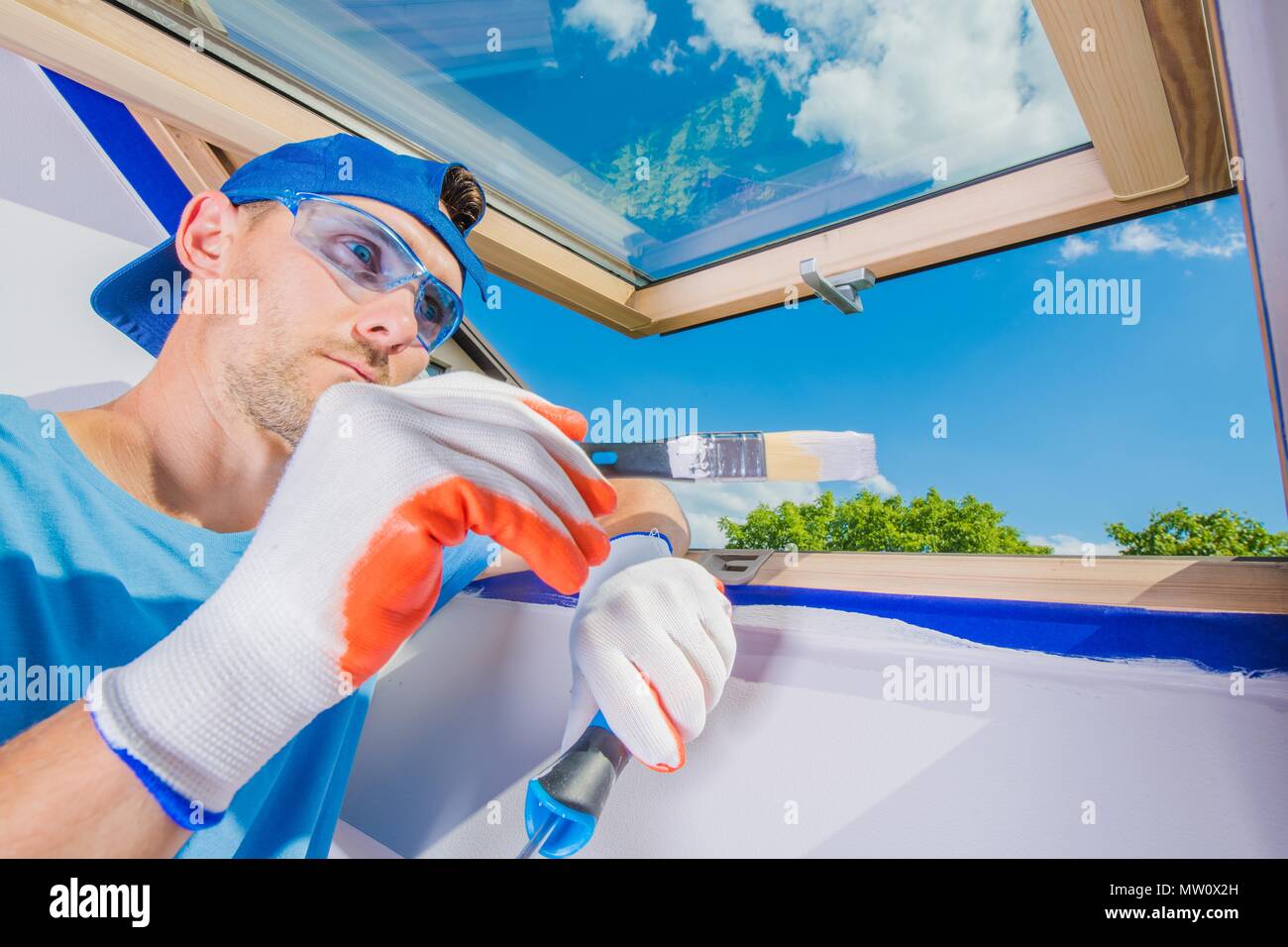 Caucasian Room Painter at Work. Finishing Window Frame Area Stock Photo