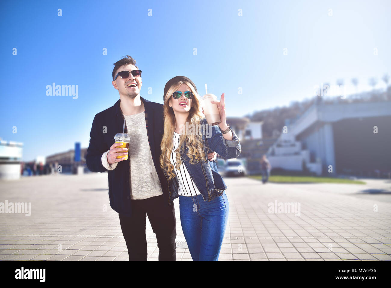 Smiling couple walk at the street in weekend and drink some cocktails. Stock Photo