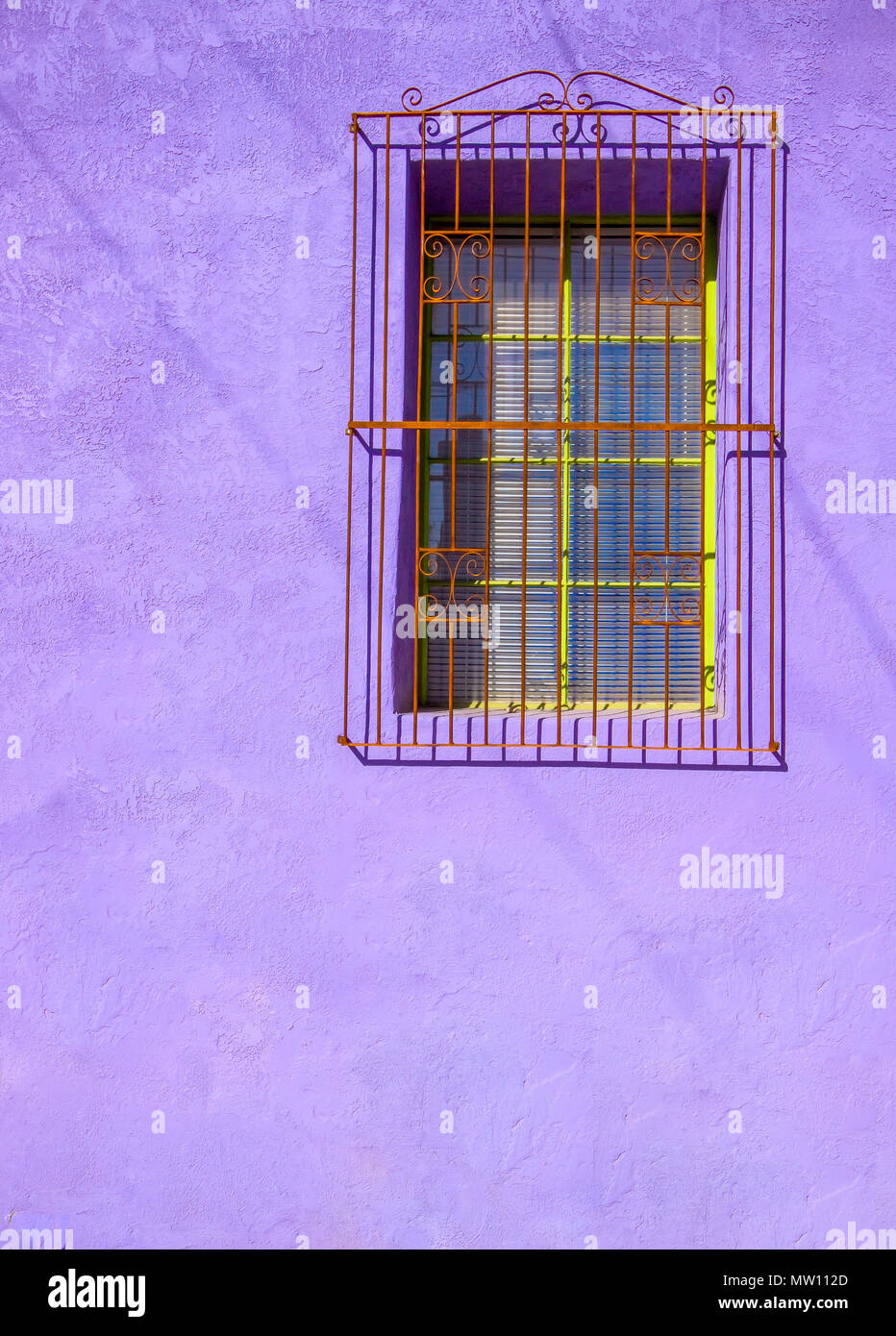 Painted Purple Stucco Wall with Barred Window Stock Photo