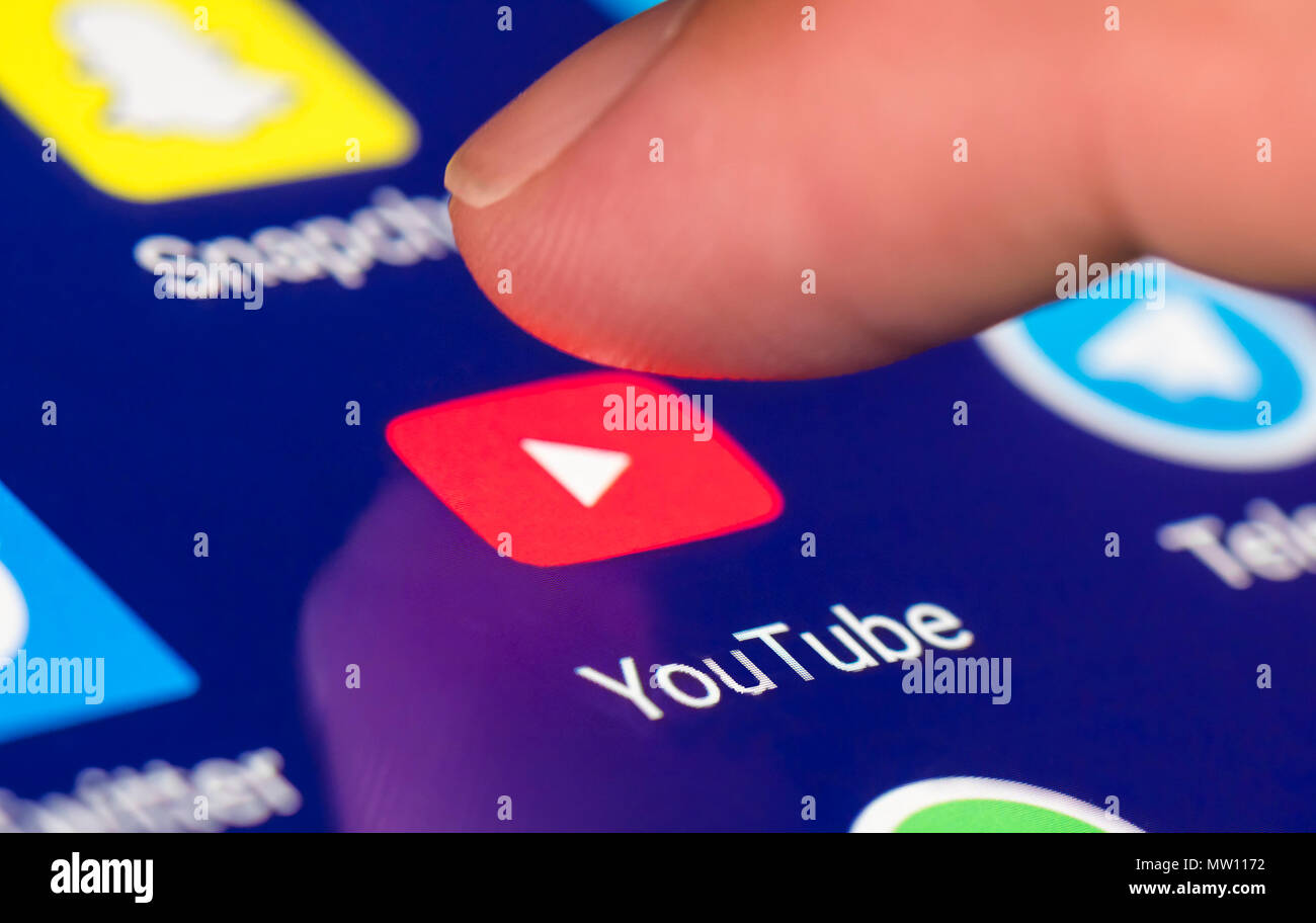 Finger pressing Youtube icon to load the app on a tablet or smartphone touchscreen. Stock Photo