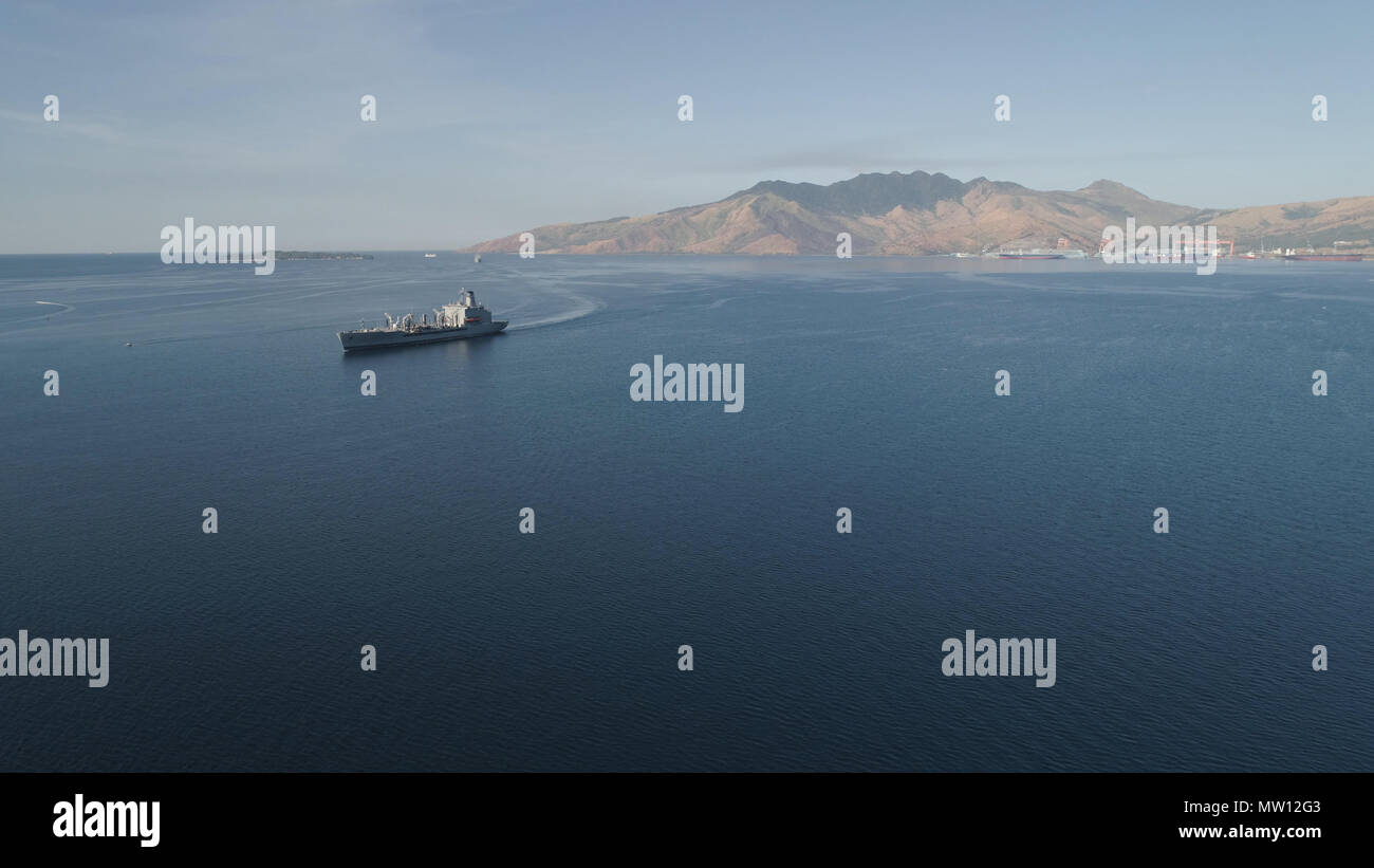 Aerial view: Cargo, Reefer ship in the sea bay. Subic Bay, Philippines, Luzon. Cargo ship in the harbor, against the backdrop of the mountains. Stock Photo