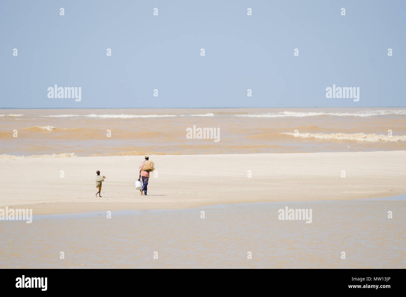 St Louis, Senegal - October 12, 2013: African fisherman and his son walking along ocean at beach. Stock Photo
