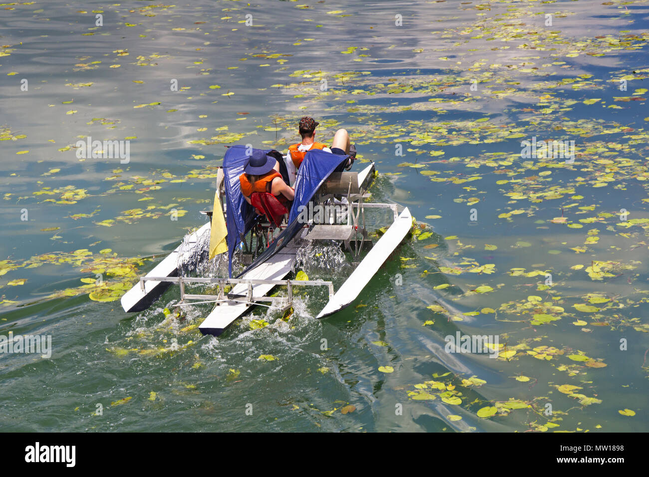 Man and woman ride with floating pedal bicycle boats across the lake Stock Photo