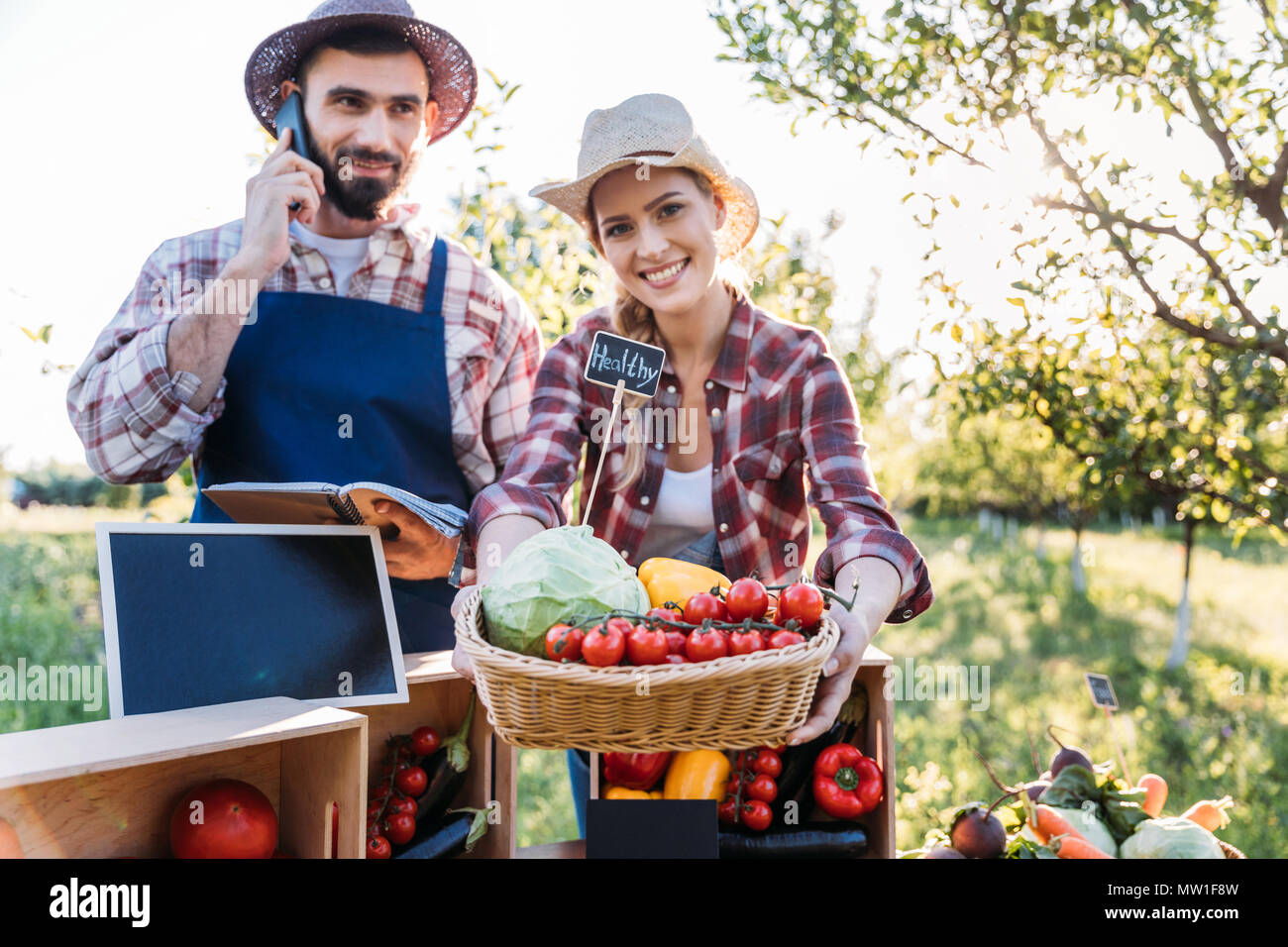 two smiling farmers selling fresh organic vegetables at market Stock ...