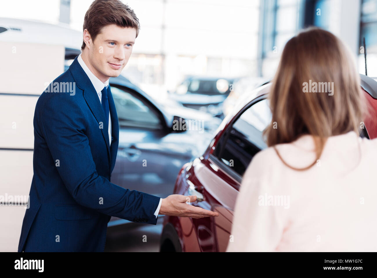 Manager inviting customer sit into a car for testdrive Stock Photo Alamy