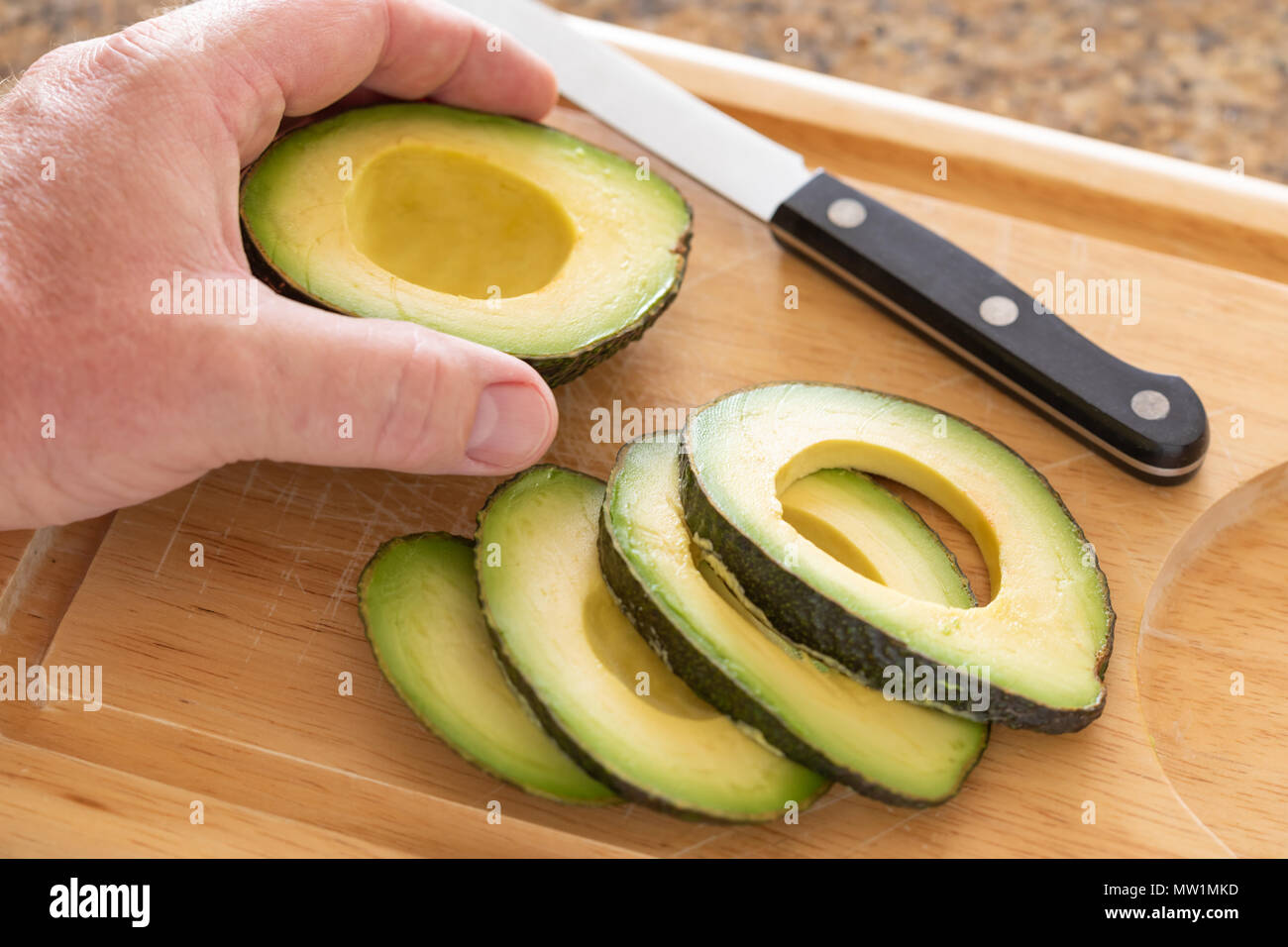 https://c8.alamy.com/comp/MW1MKD/male-hand-prepares-fresh-cut-avocado-on-wooden-cutting-board-MW1MKD.jpg