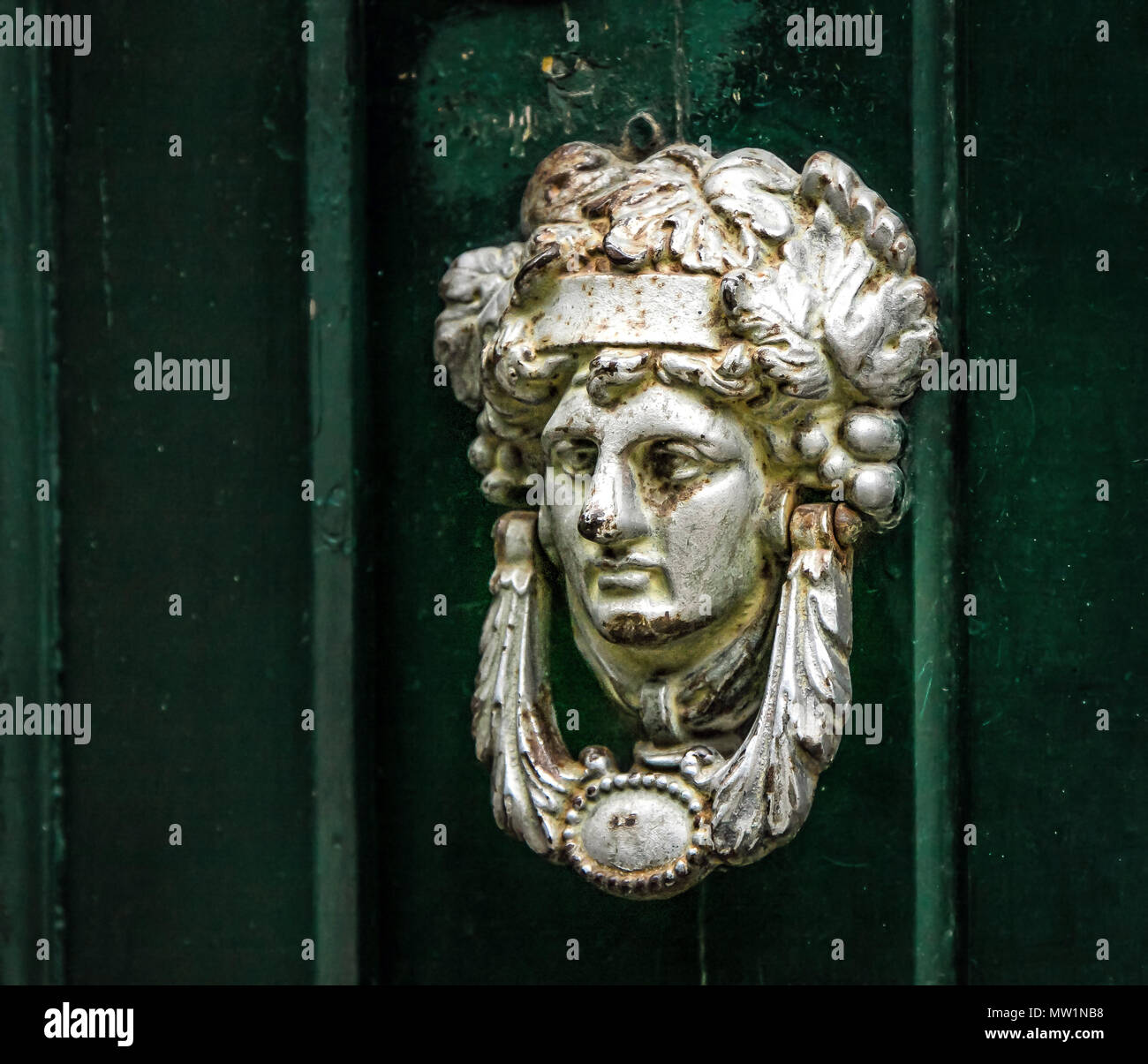 Decorative knocker made as a man's head on a green door. Stock Photo