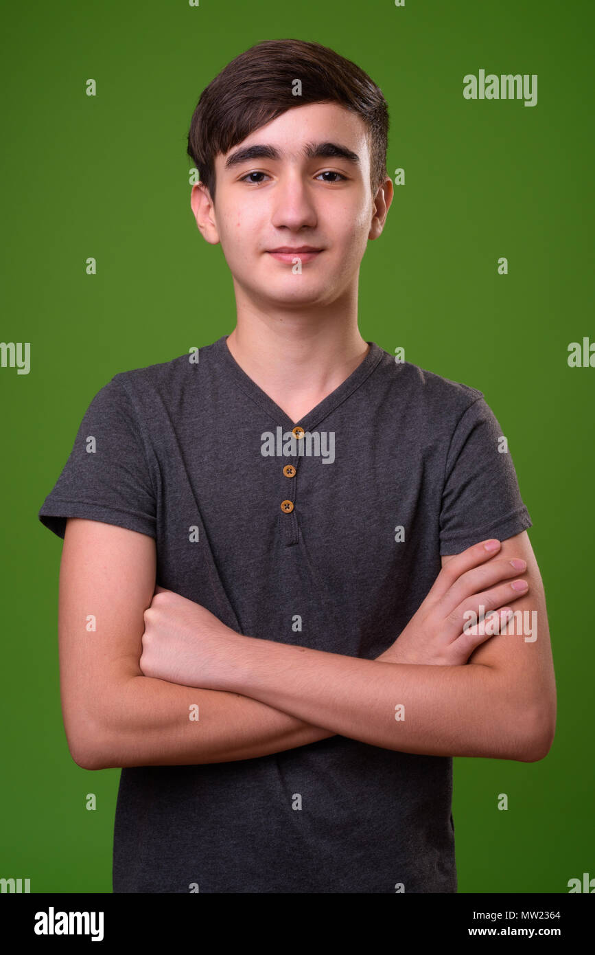 Young handsome Iranian teenage boy against green background Stock Photo