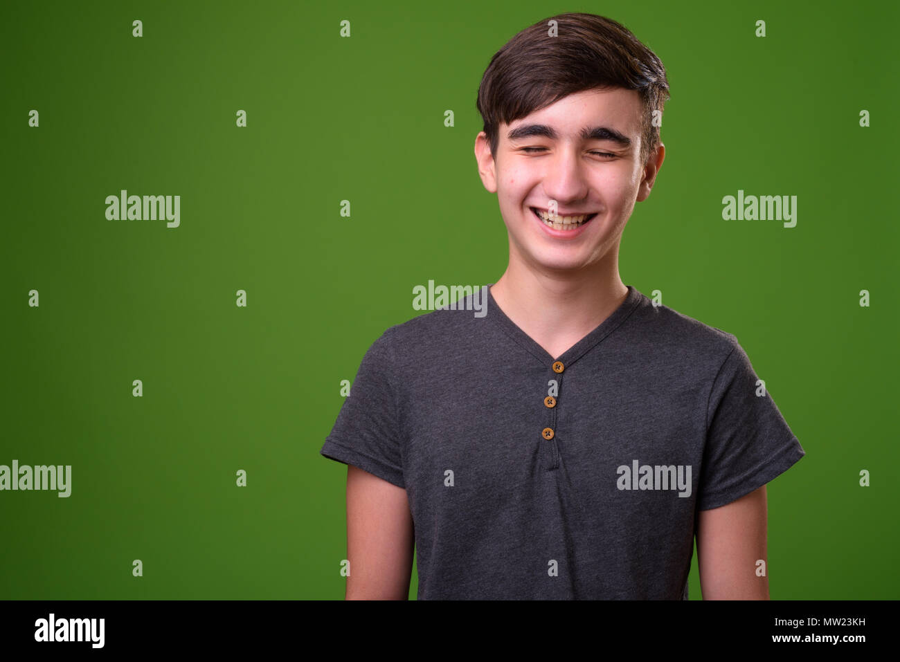 Young handsome Iranian teenage boy against green background Stock Photo
