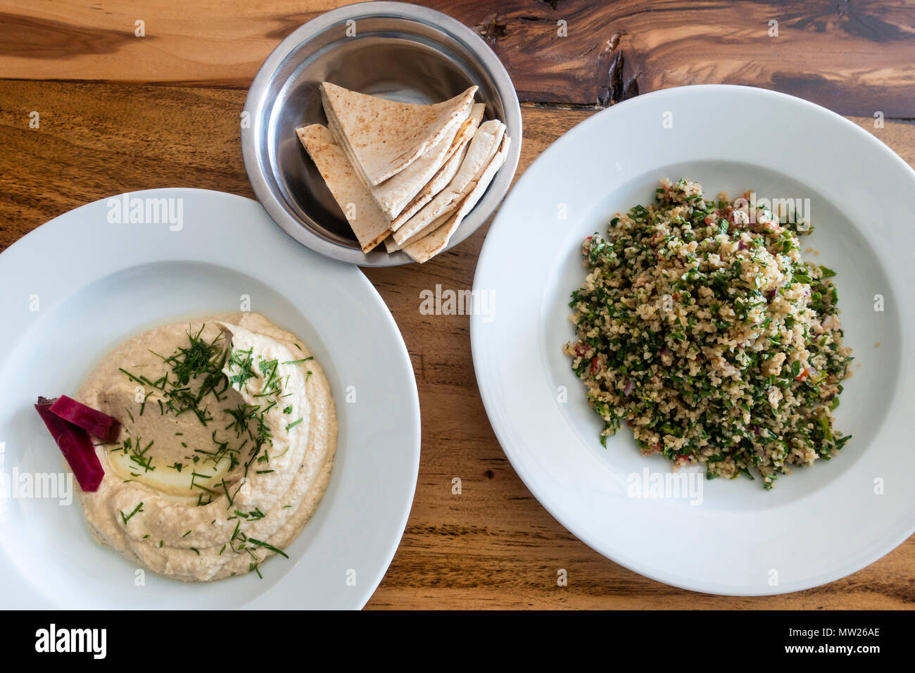 Mediterranean food on a wooden table, includes baba ganoush dip, tabbouleh, and pita bread Stock Photo
