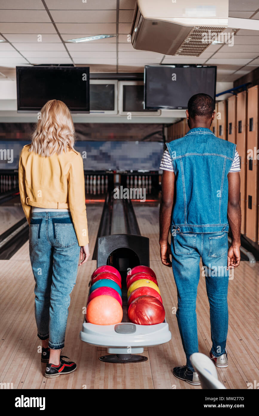 rear view of multiethnic couple standing near stand with balls at bowling club Stock Photo Alamy