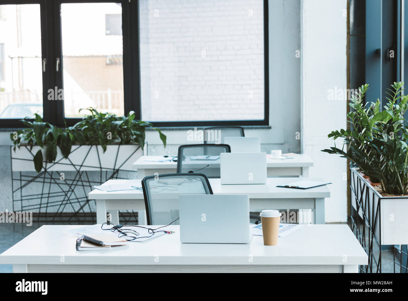 headsets and laptops on tables in light empty office Stock Photo