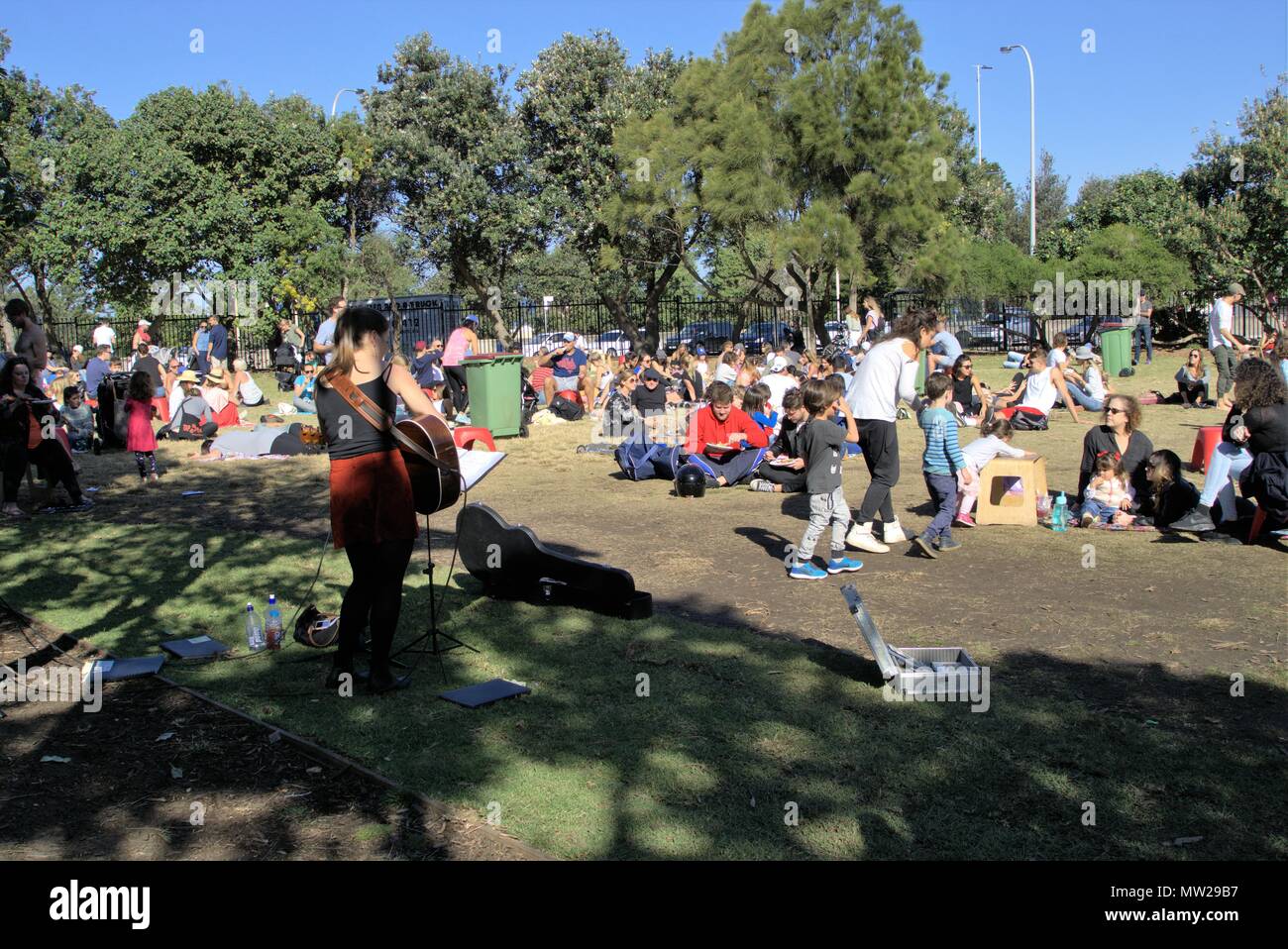 People relaxing in Sydney park, Bondi Australia. People enjoying day out sitting in park at Bondi Farmers Market. People of all ages sitting in sun. Stock Photo