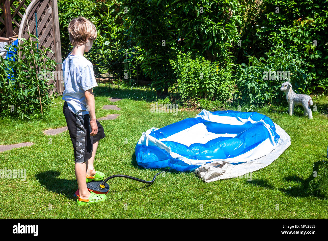 Little boy blowing up inflatable swimming pool with belows Stock Photo