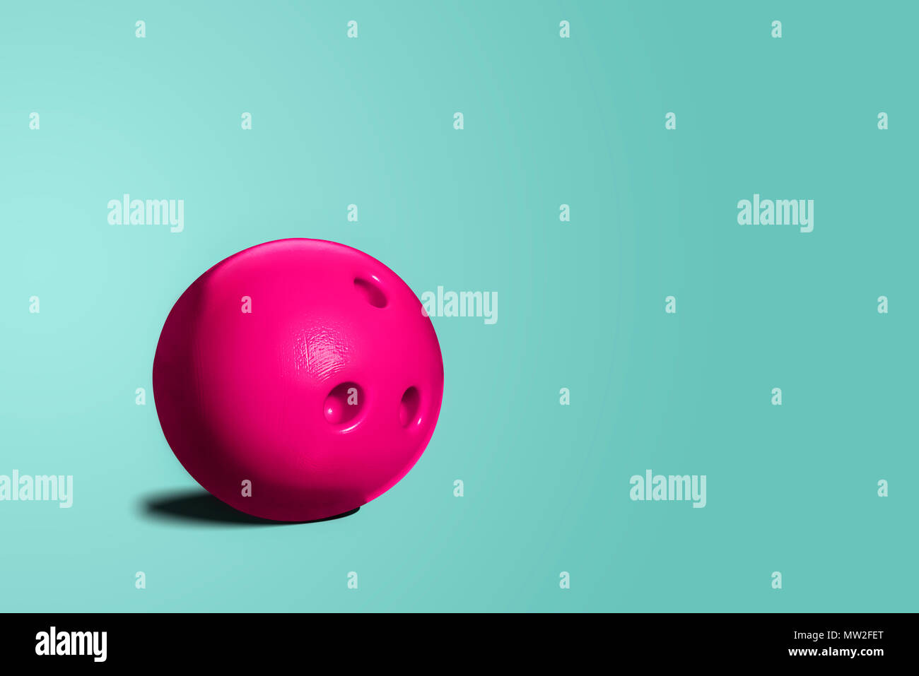 Pink bowling ball. A toy bowling ball of pink color on a blue