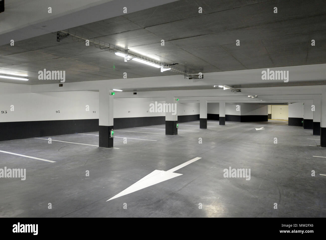 Underground parking lot of a private apartment block: parking place marked out by floor markings and arrows on the ground Stock Photo