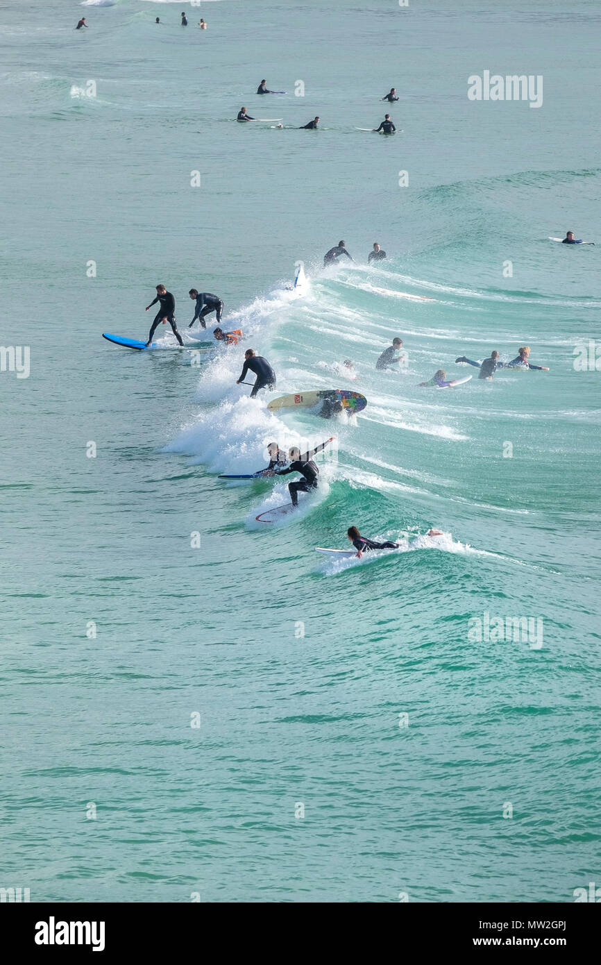 Surfers on a wave at Fistral in Newquay in Cornwall. Stock Photo