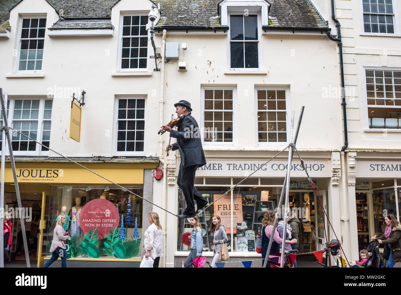 A street entertainer playing the violin and balancing on a slack line in Pydar Street in Truro City centre in Cornwall. Stock Photo