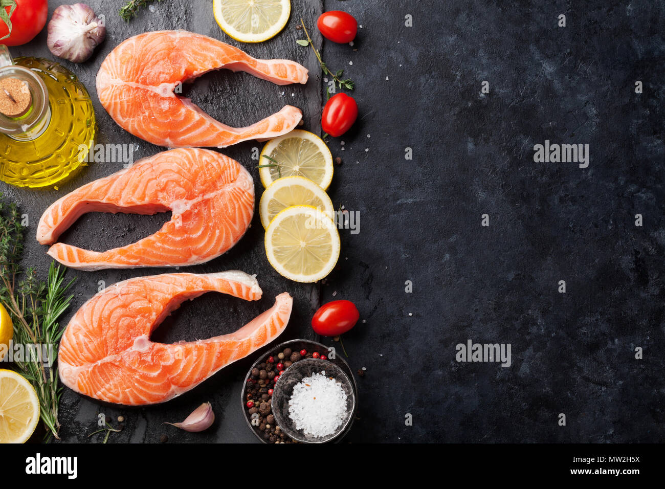 Raw salmon fish steaks with spices cooking on cutting board. Top view ...