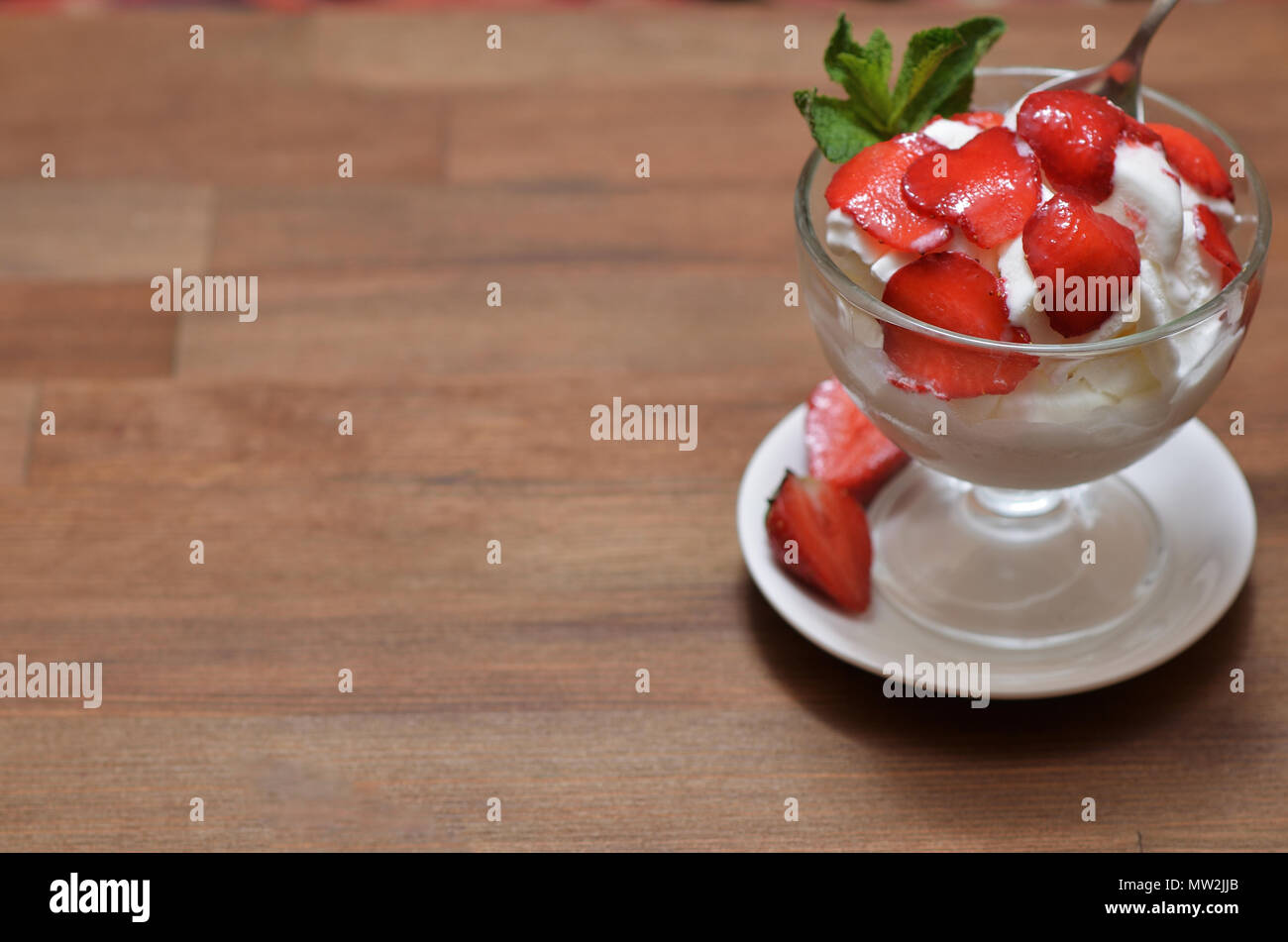 Vanilla ice cream with sliced strawberries and mint in a glass bowl on ...