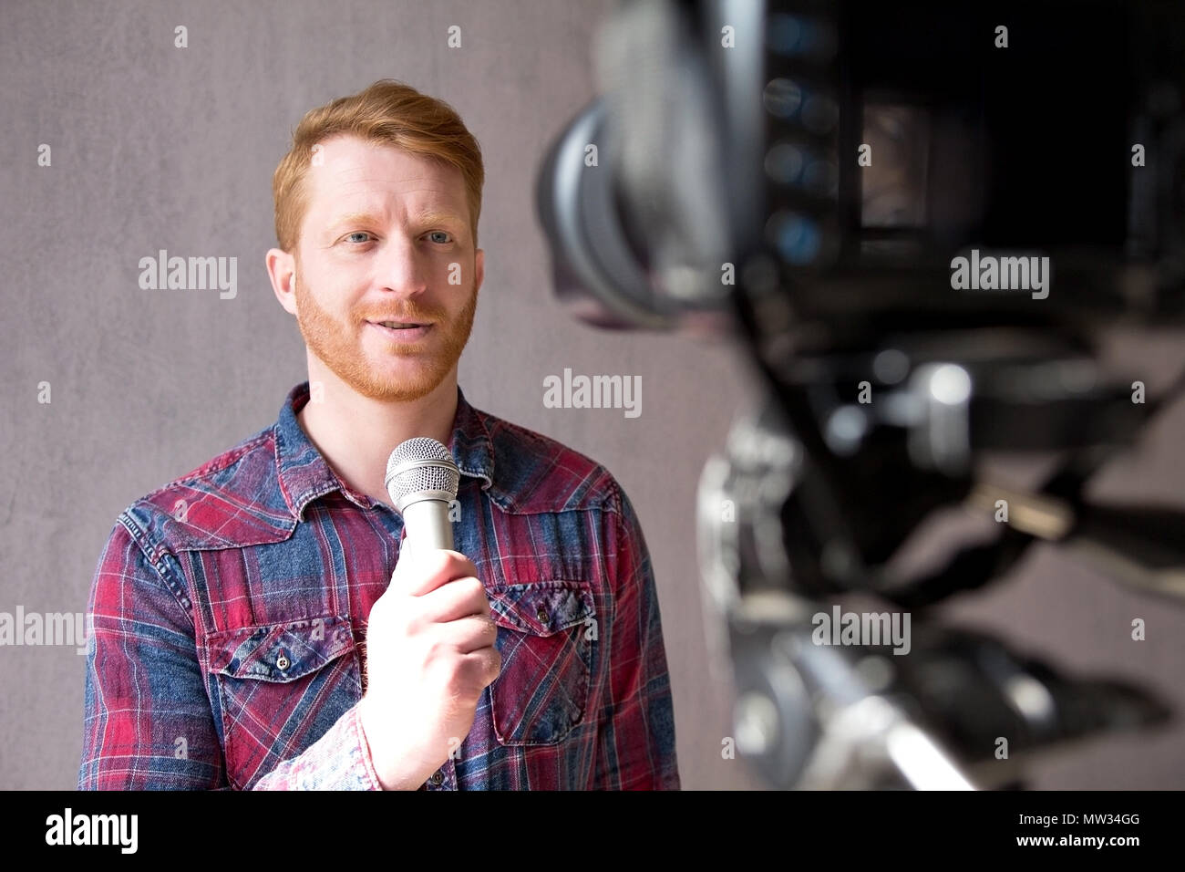 Attractive man with microphone in front of camera. Stock Photo