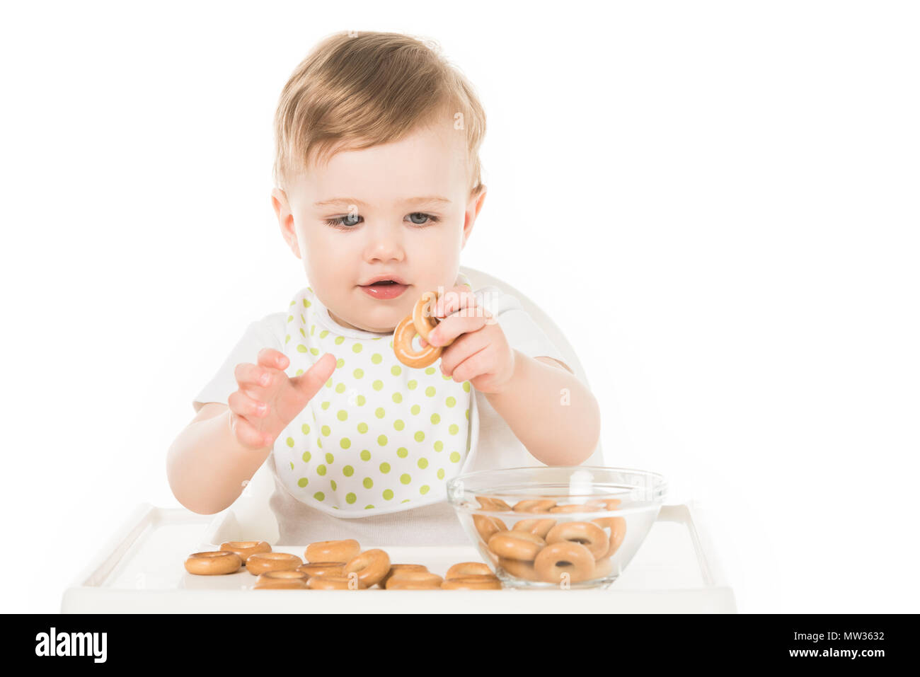 happy baby boy eating bagels in highchair isolated on white background