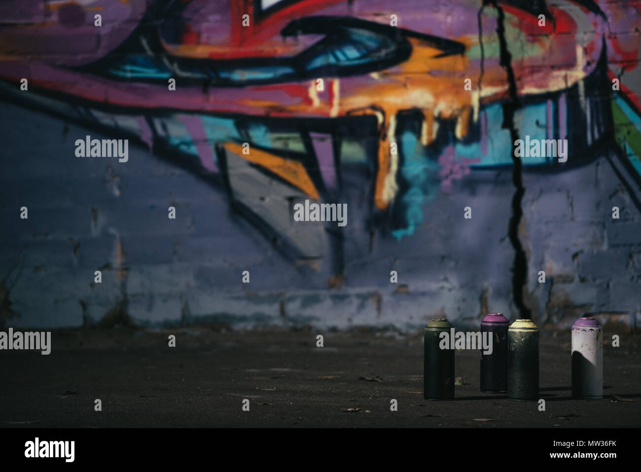colorful graffiti on wall cans with aerosol paint standing on ...