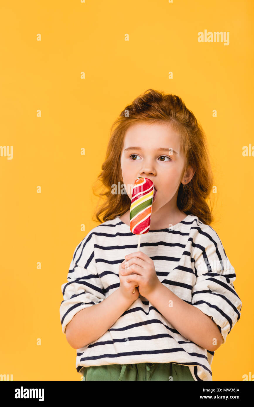 portrait of preteen child eating lollipop isolated on yellow Stock Photo