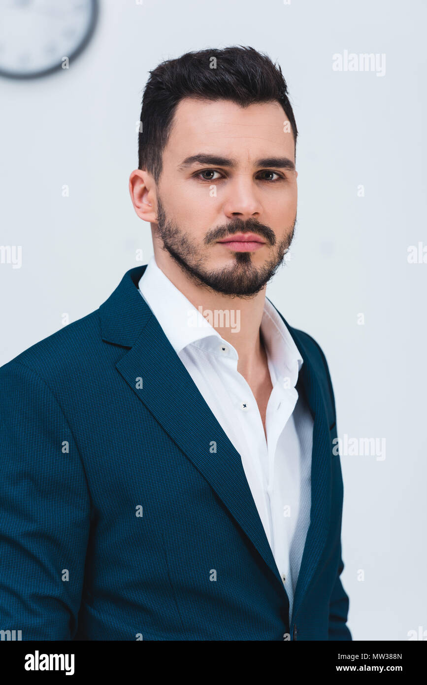 portrait of handsome young businessman in formal wear looking at camera ...