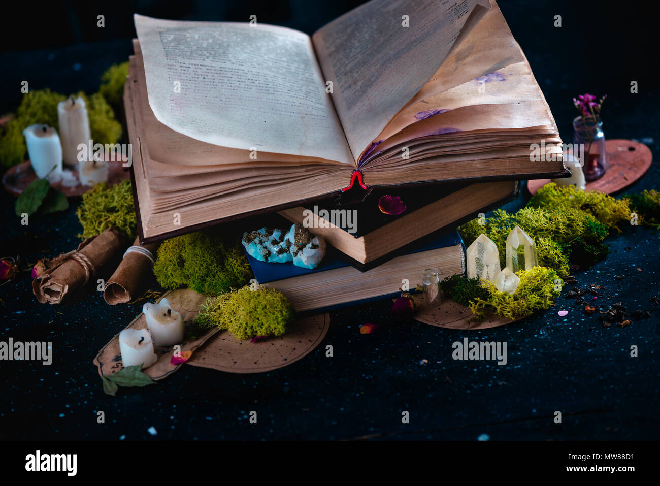 Open book with candles, crystals, and moss. Reading fantasy concept with copy space. Magical still life on a dark background with occult equipment. Stock Photo