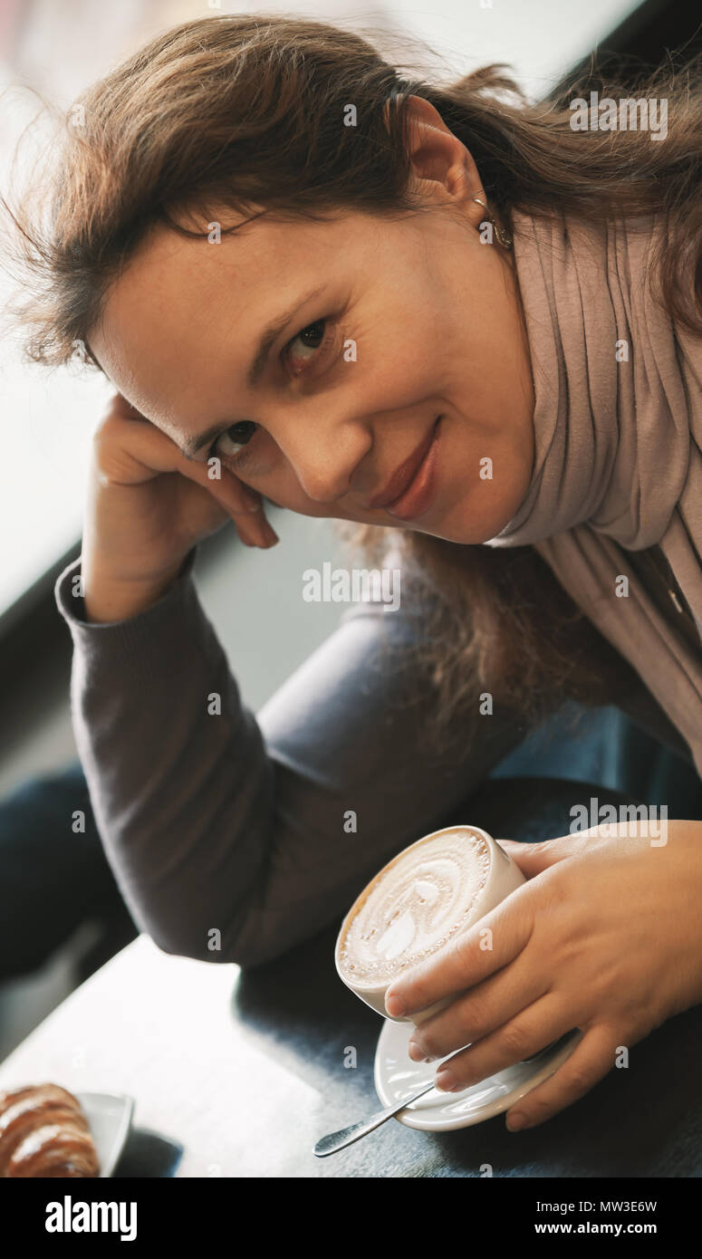 Young adult European woman drinks cappuccino coffee Stock Photo