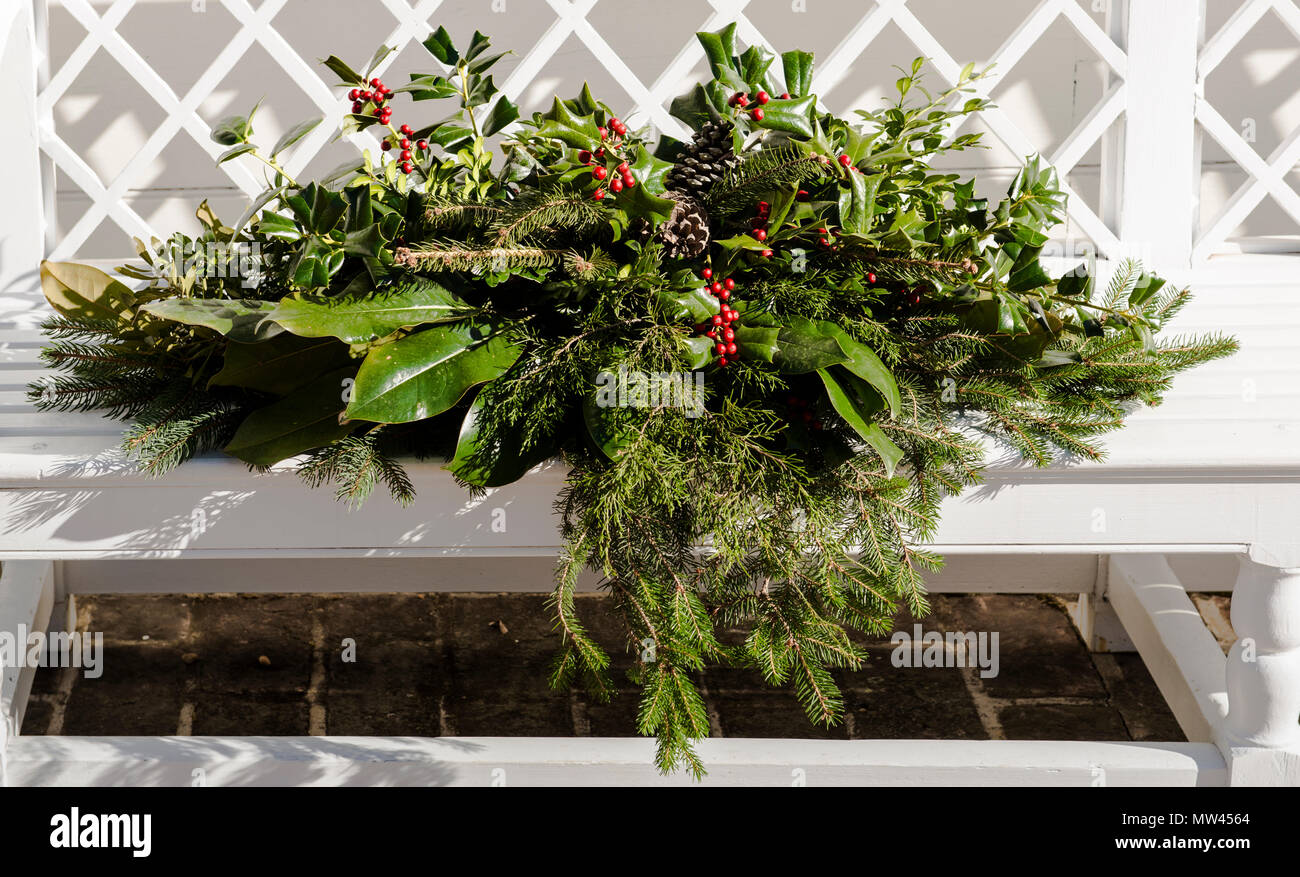 Closeup: Holly wreath & display on a white bench on the property of the historic Rockefeller home in Colonial Williamsburg, VA. Basset Hall/Christmas. Stock Photo