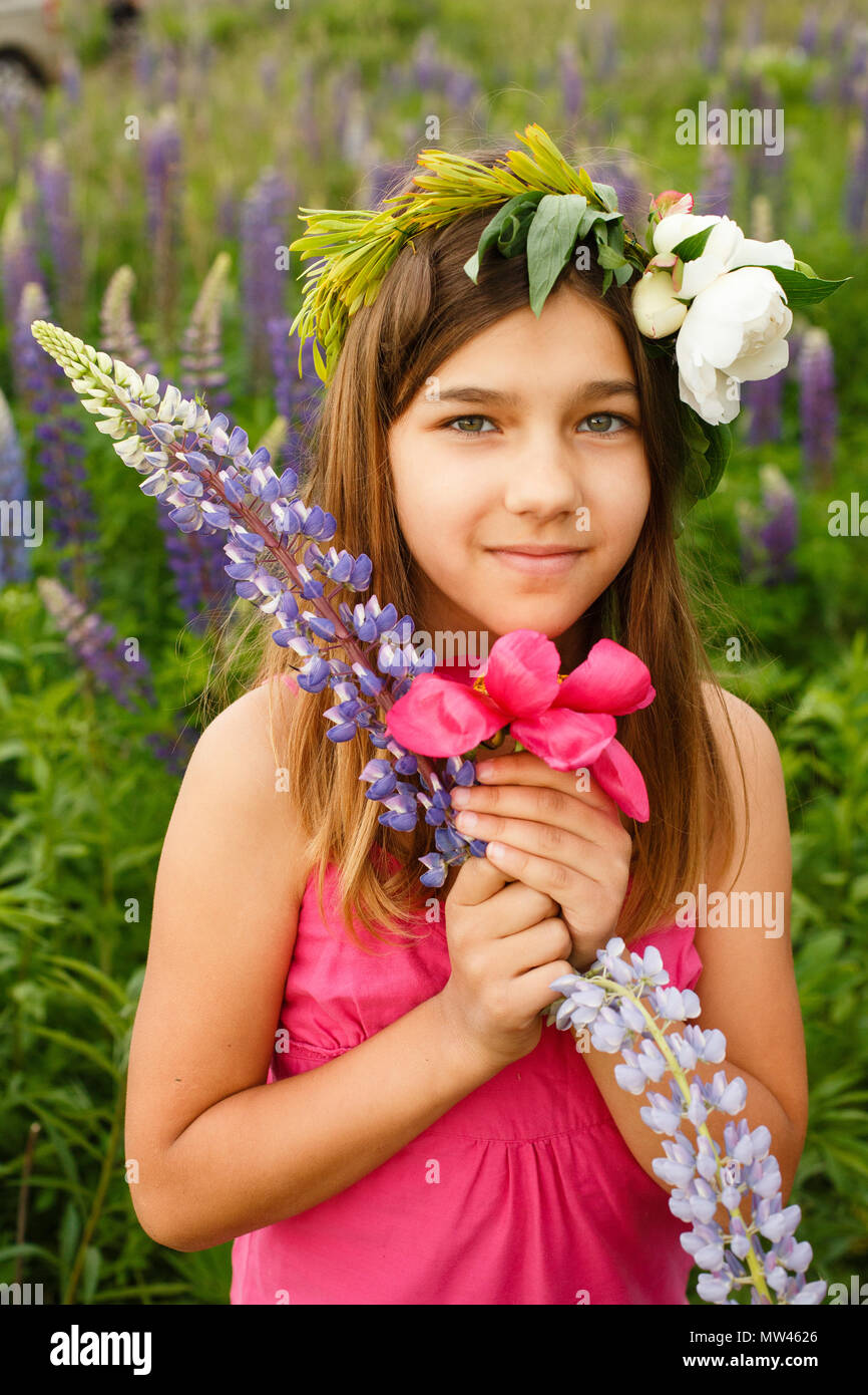 Beautiful girl smiling in a pink dress in lupins field. Blooming ...