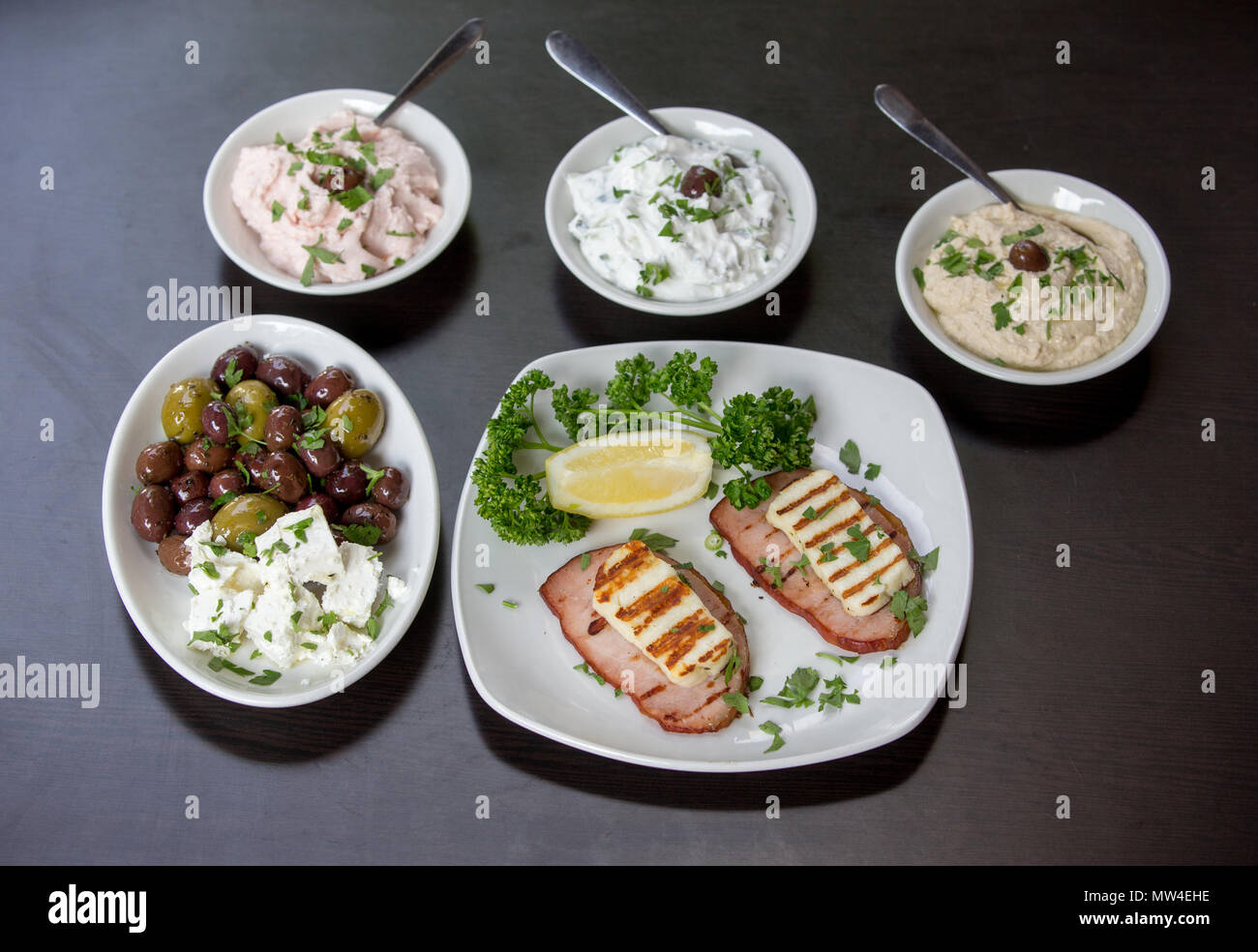 Grilled Haloumi on Ham with an Olive and Feta salad, Taramasalata, Tzatziki and Houmous Stock Photo