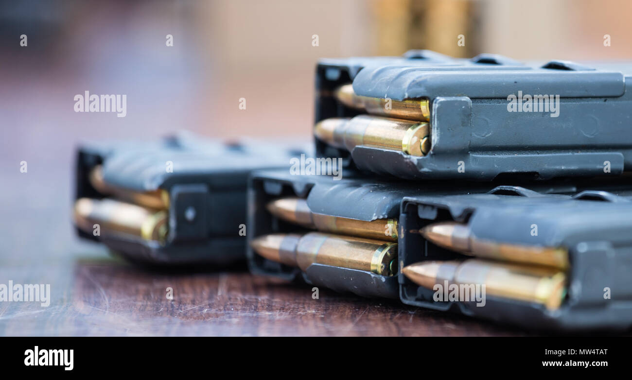Blue magazines with bullets of firearm putted on wooden table ...