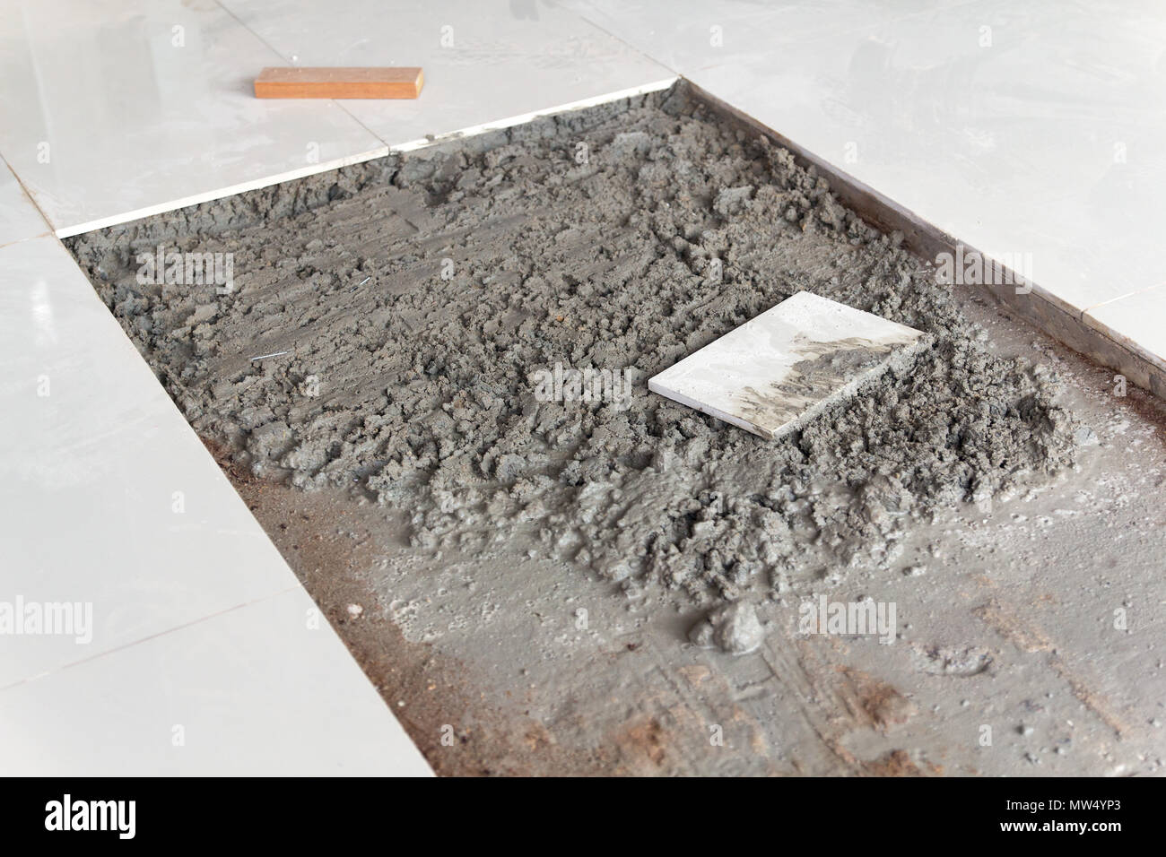 Placing ceramic floor tile in position over adhesive Stock Photo