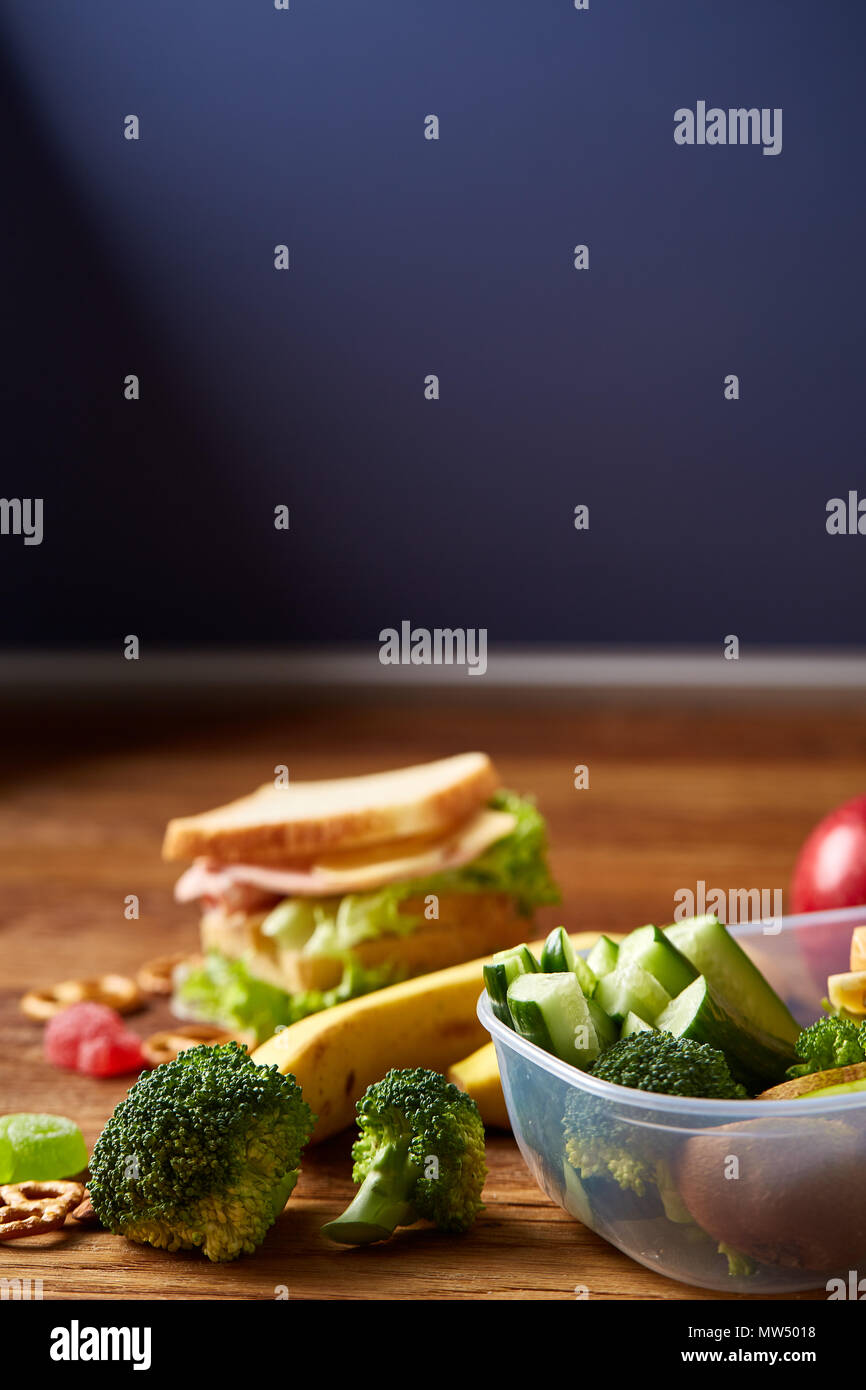 Back to School concept, school supplies, assortment of biscuits and transparent lunchbox full of sandwich, fruits and vegetables togather with assortm Stock Photo