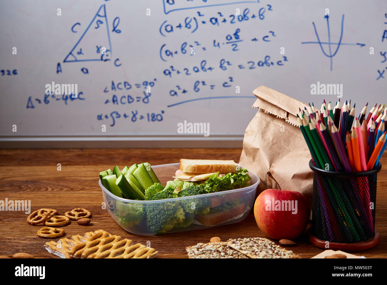 Back to School concept, school supplies, assortment of biscuits and transparent lunchbox full of sandwich, fruits and vegetables togather with assortm Stock Photo