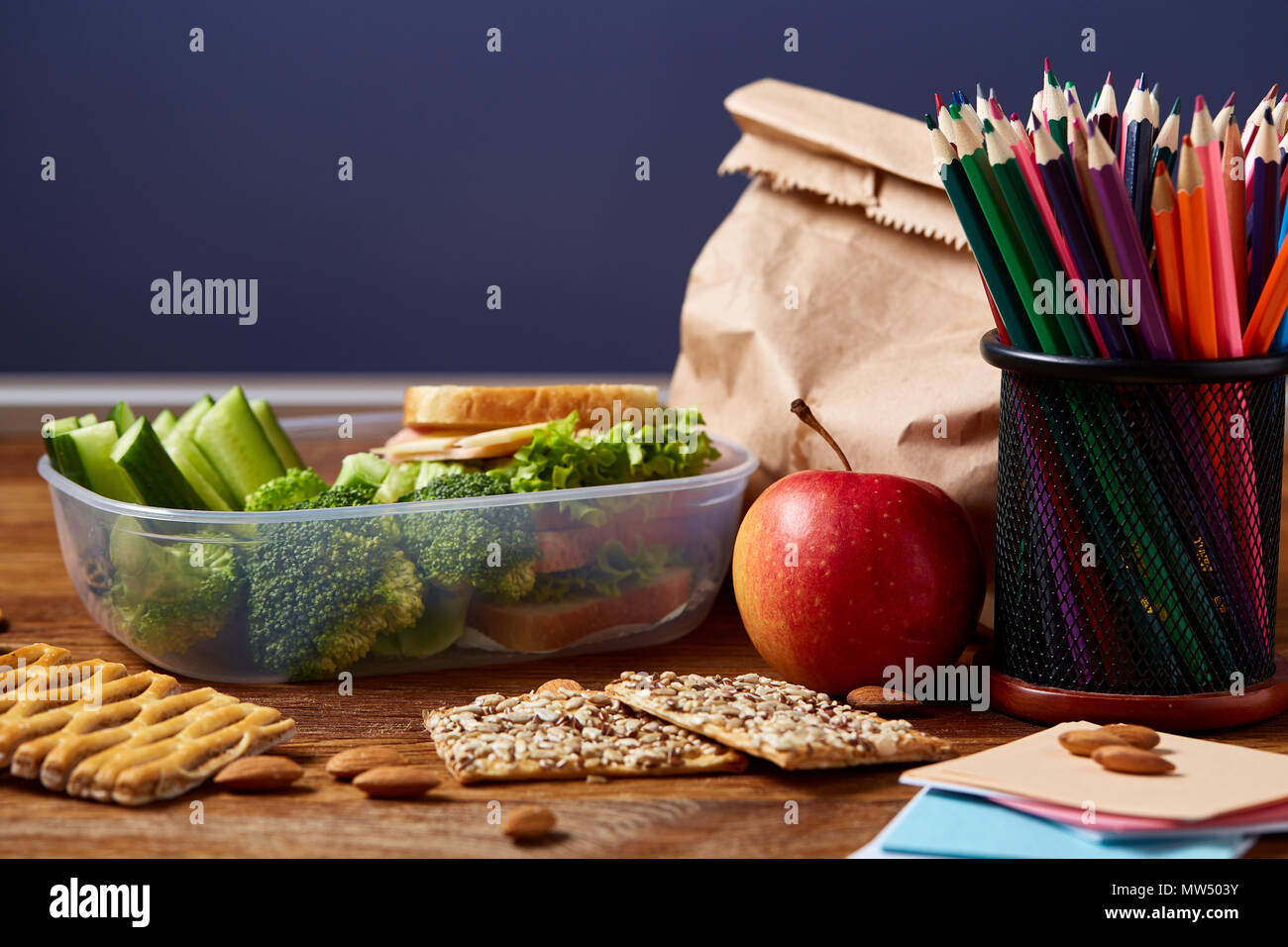 Back to School concept, school supplies, assortment of biscuits and transparent lunchbox full of sandwich, fruits and vegetables togather with assortm Stock Photo