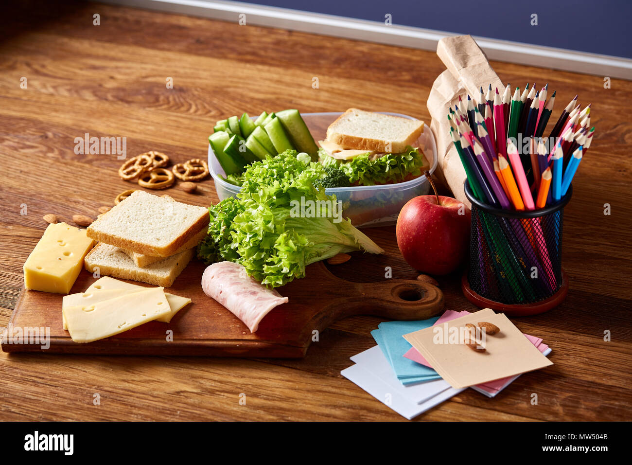 Back to School concept, school supplies, assortment of biscuits and transparent lunchbox full of sandwich, fruits and vegetables togather with assortm Stock Photo