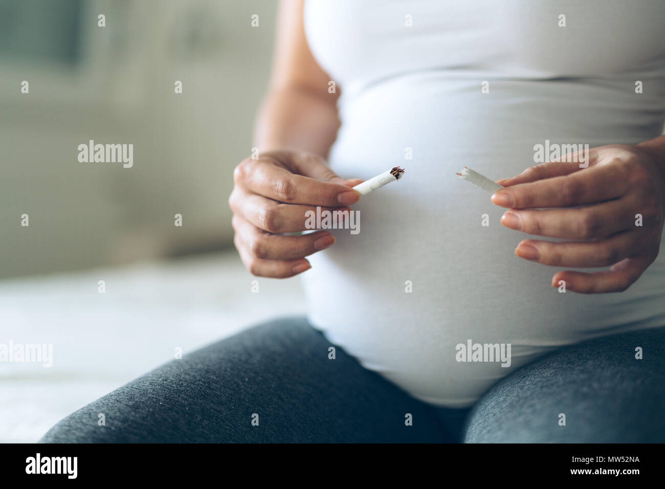 Health minded pregnant woman breaks last cigarette Stock Photo