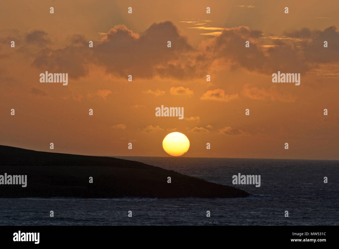 Winter solstice morning Shetland sunrise on a calm day with golden glow of the sun peaking over the horizon Stock Photo