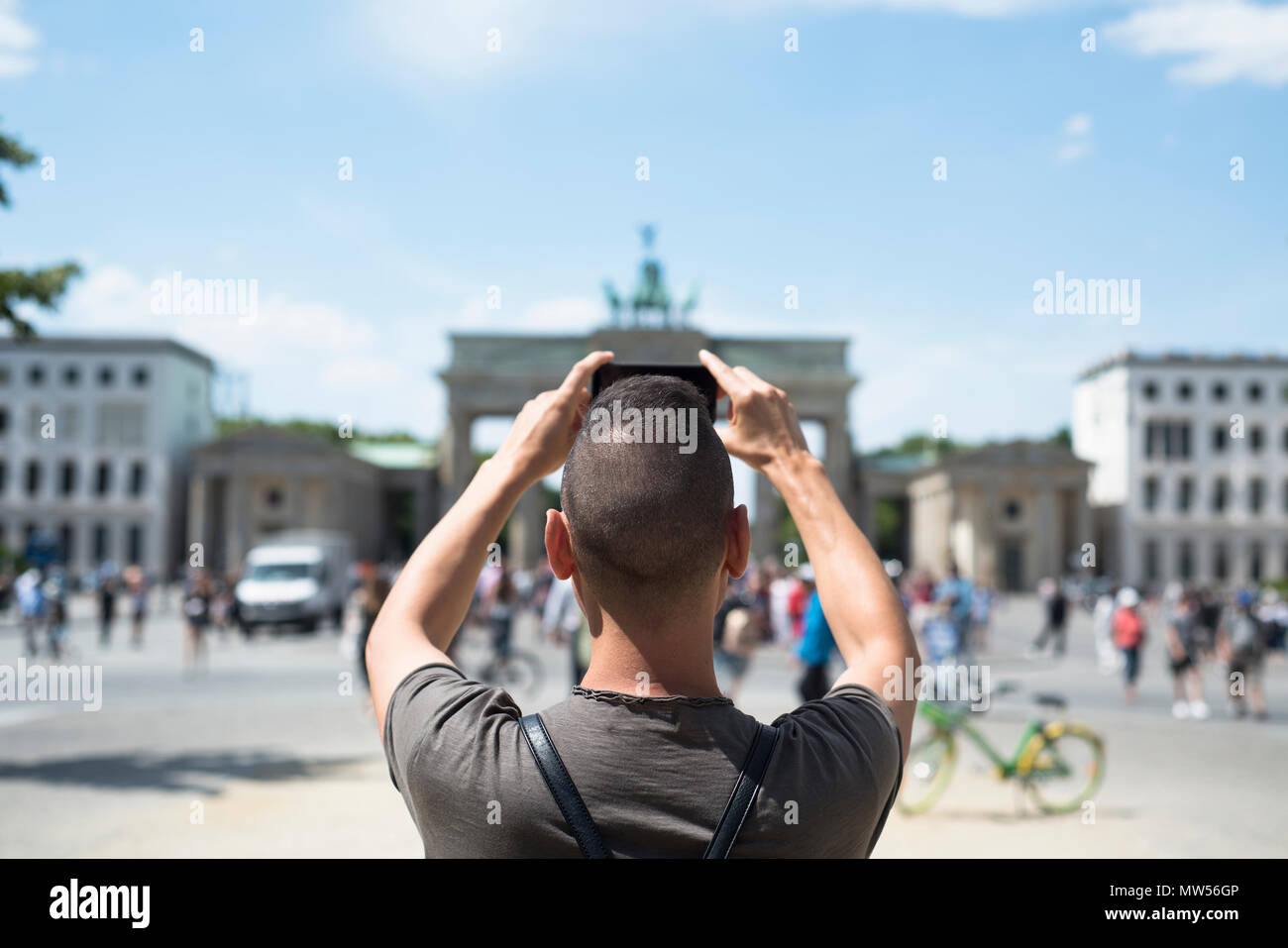 closeup of a young caucasian man, seen from behind, taking a picture of the popular Brandenburg Gate in Berlin, Germany, with his smartphone Stock Photo