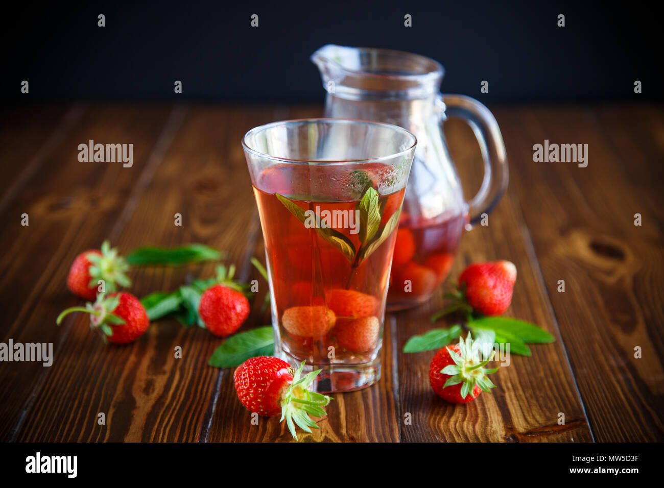 Sweet compote of ripe red strawberries in a glass decanter on a table Stock Photo