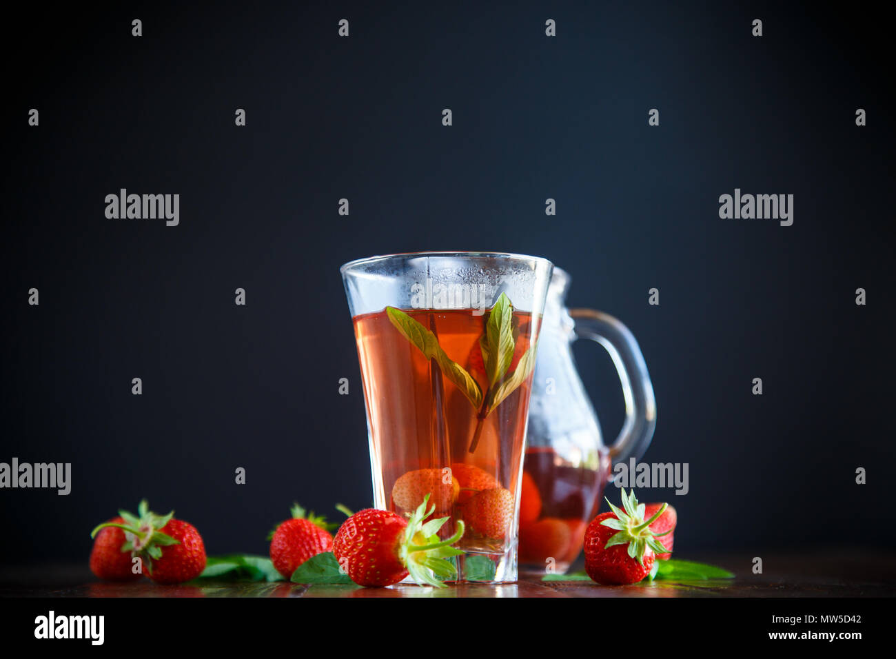 Sweet compote of ripe red strawberries in a glass decanter on a black background Stock Photo