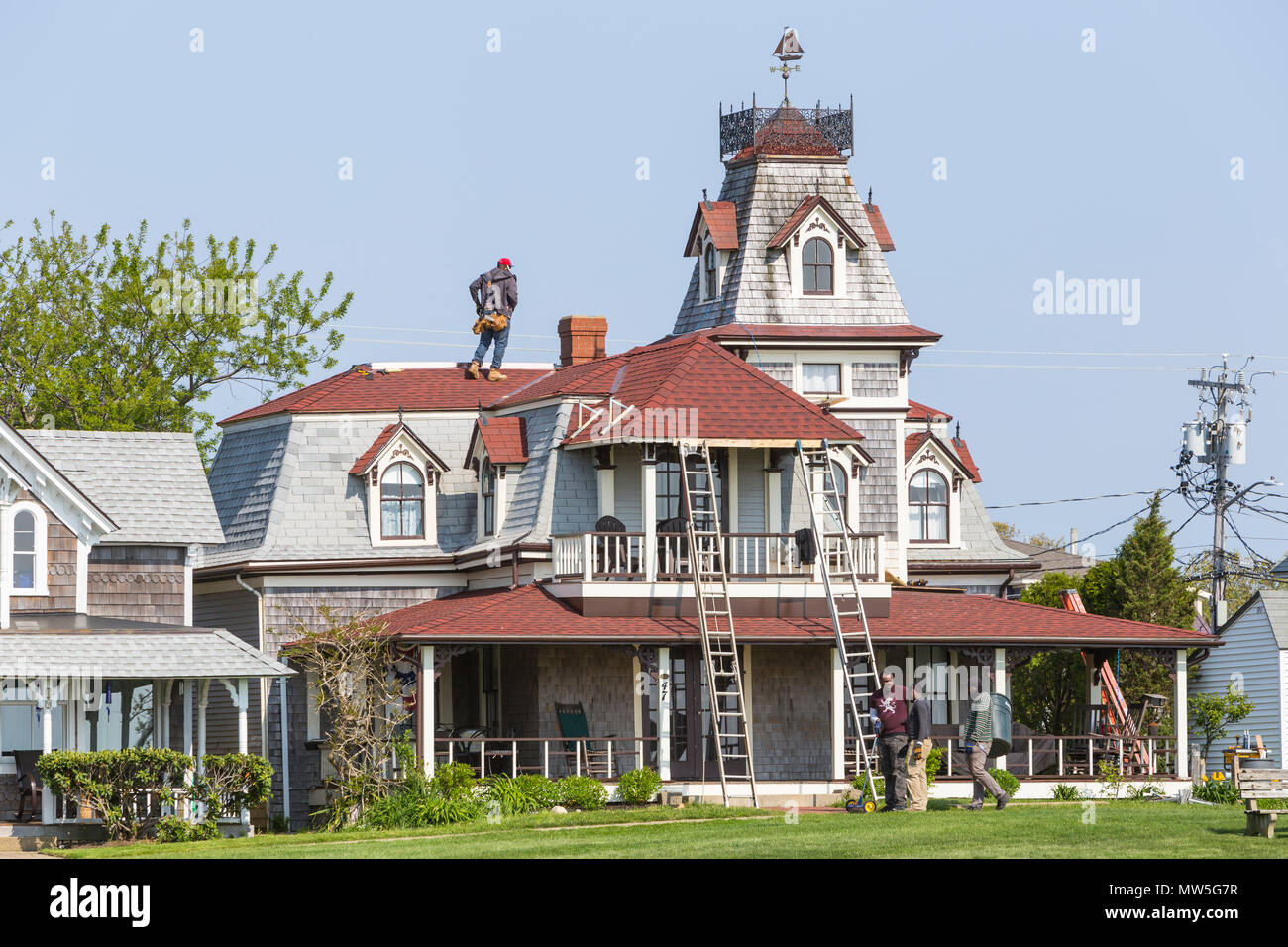 Workers make spring roof repairs to a Victorian era home on Ocean Avenue in Oak Bluffs, Massachusetts on Martha's Vineyard. Stock Photo