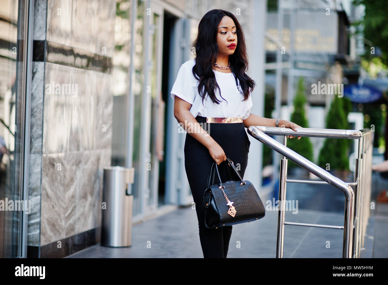 Stylish african american business woman with handbag on streets of city ...