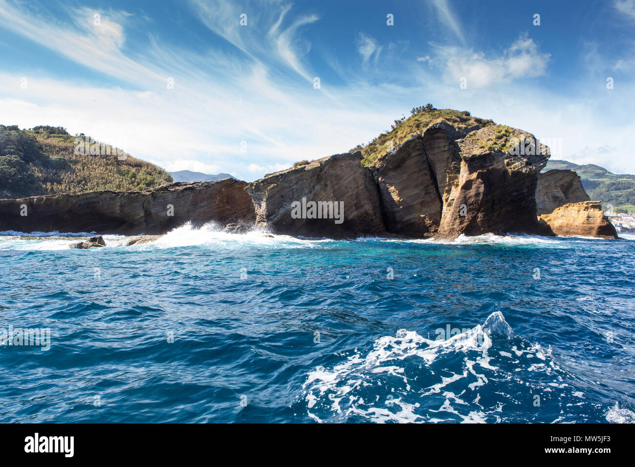 layered basalt rock formations of islet Stock Photo