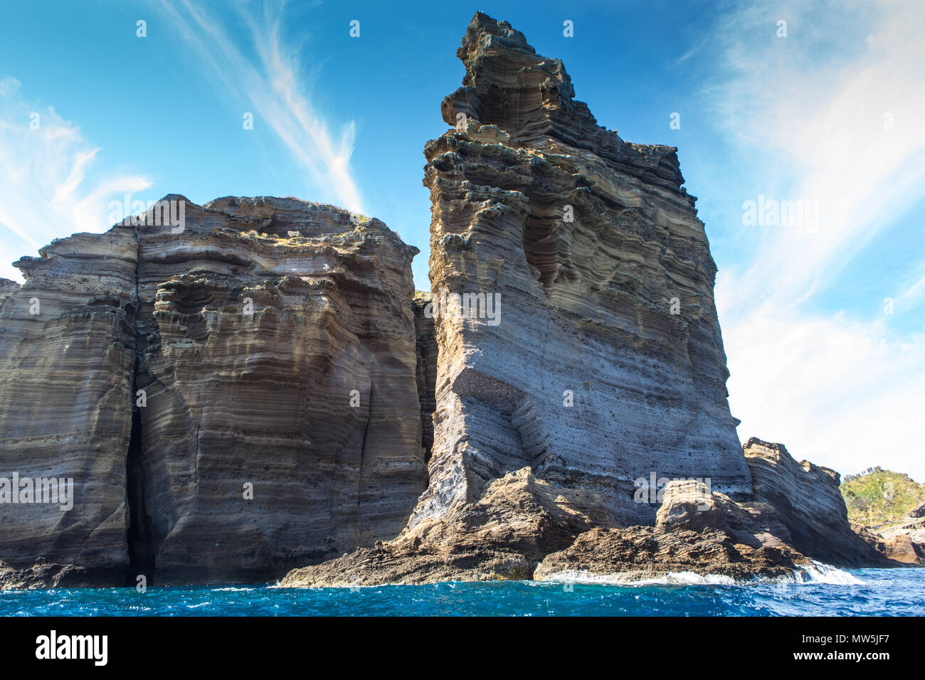 layered basalt rock formations of islet Stock Photo