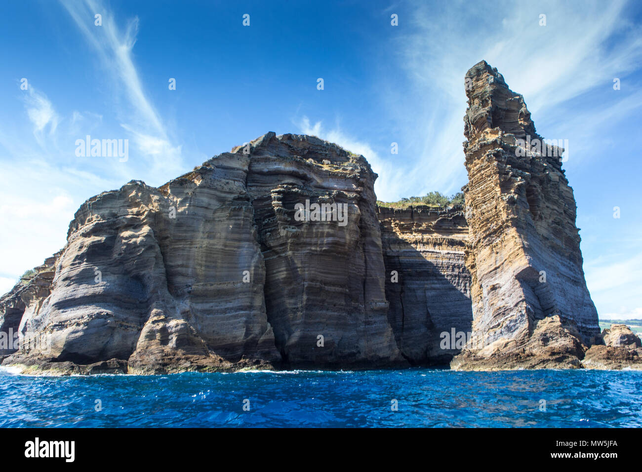 layered basalt rock formations of islet Stock Photo